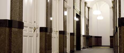Un pasillo con columnas, puertas y lámparas colgantes.