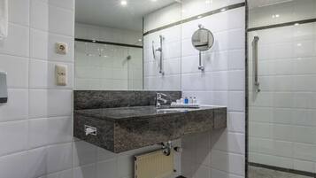 A modern bathroom with a black marble floor, a white toilet, a sink with a mirror, and a glass shower enclosure.