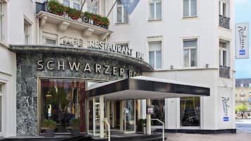 L’entrée d’un hôtel, avec une enseigne indiquant « Café-restaurant » et « Schwarzer Bar ».