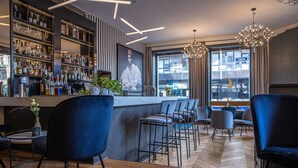 Un área de bar moderna con taburetes altos, una barra y una variedad de botellas y vasos.