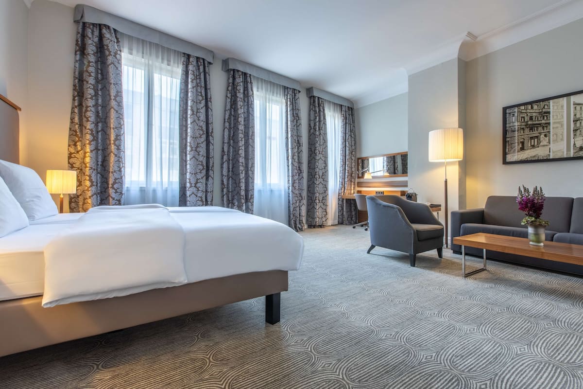 Une chambre d’hôtel avec un lit, un bureau, un canapé et une lampe.