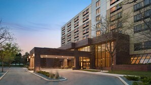 A modern hotel with a brick facade, large windows, and a covered entrance area. - DoubleTree by Hilton St. Paul East (St. Paul)