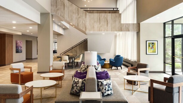 A spacious lobby with a high ceiling, modern seating arrangements, and a staircase leading to an upper level. - DoubleTree by Hilton St. Paul East (St. Paul)