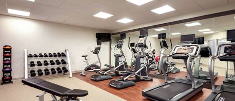 A gym with treadmills, elliptical machines, and a bench.