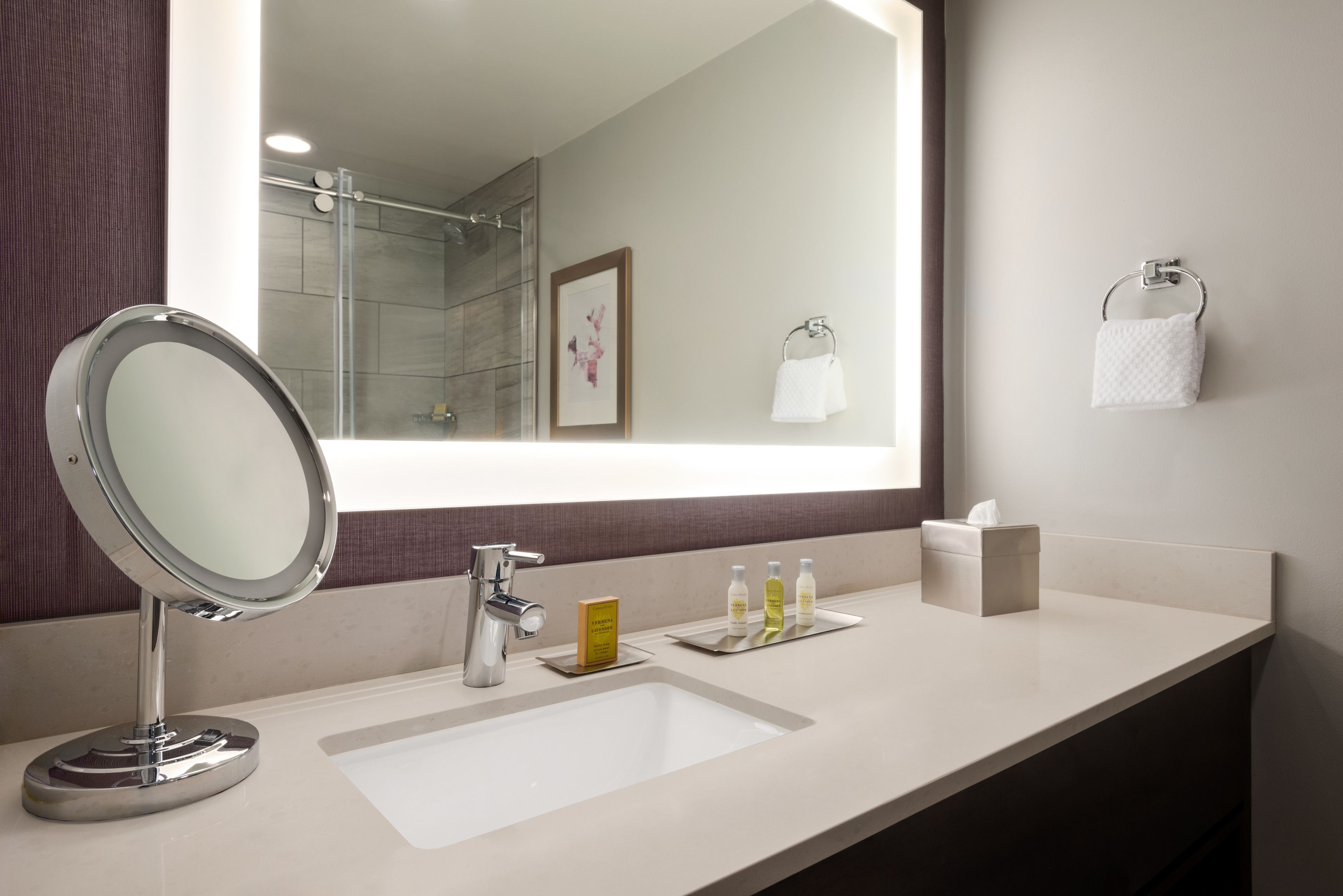 A modern bathroom with a large mirror, a sink, and a shower area.