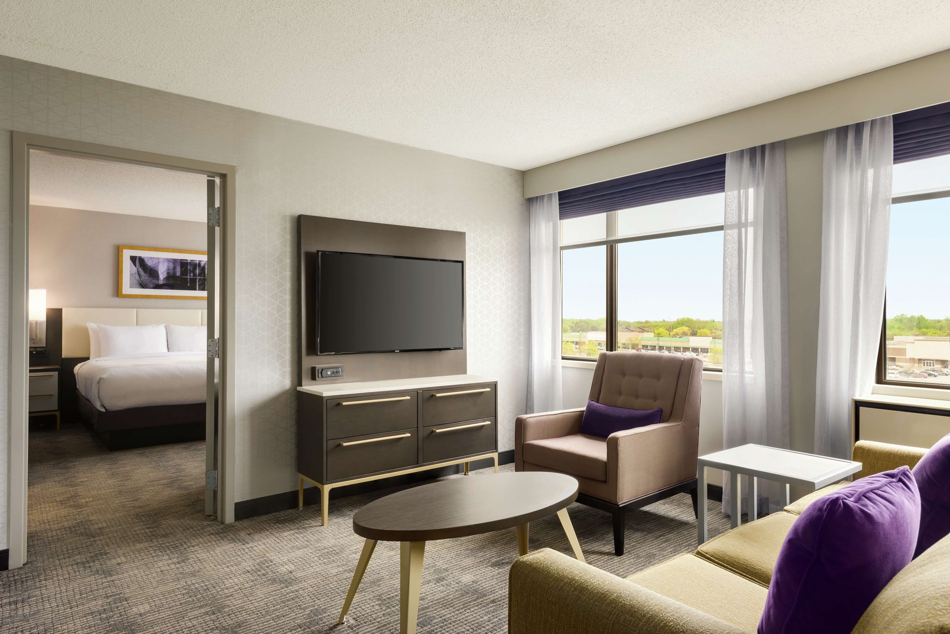 Une chambre d’hôtel avec un lit, une télévision, un canapé, une petite table et une fenêtre donnant sur un beau paysage.
