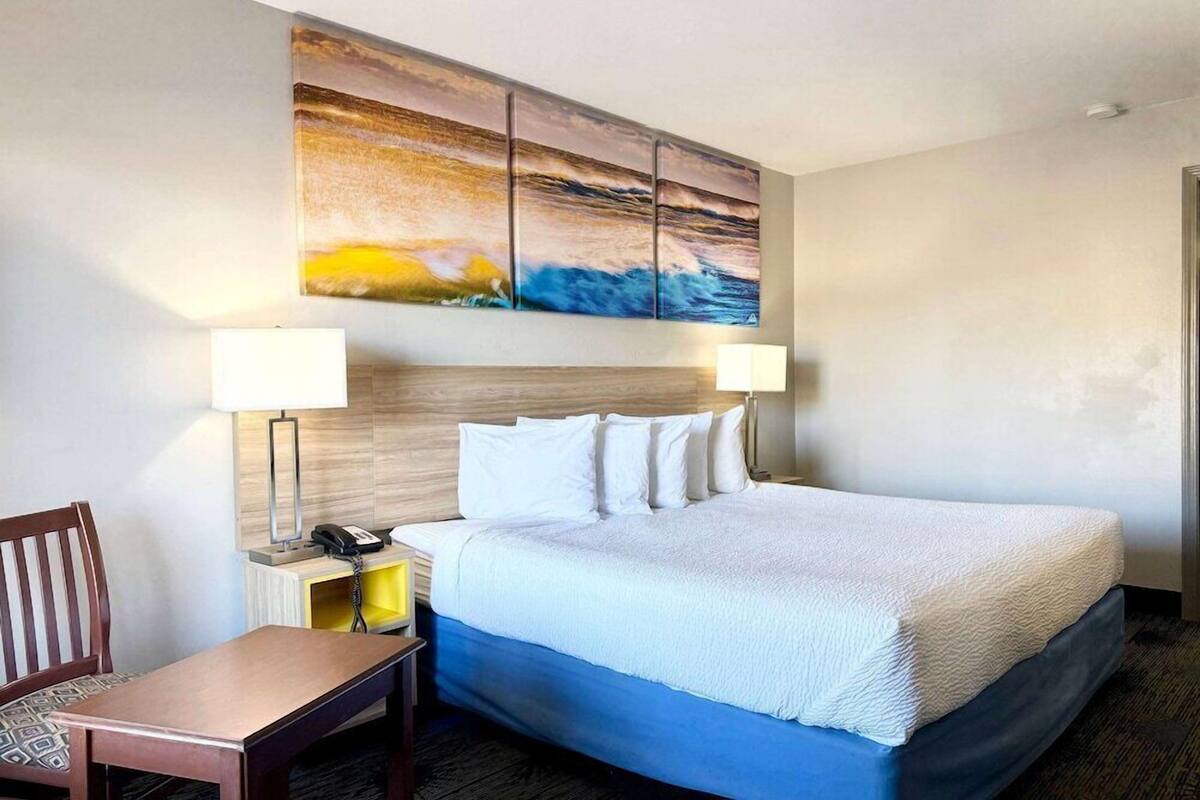 A hotel room with a bed, two bedside lamps, a desk, and a chair.