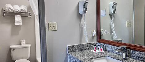 A bathroom with a toilet, a sink, a mirror, and a towel rack.