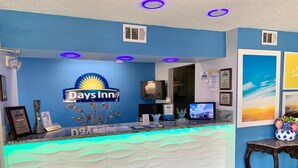 A reception area with a Days Inn sign, a reception desk, a television, framed certificates, and a wall with framed pictures.