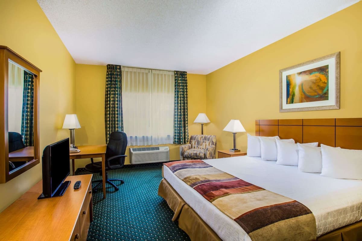Ein Hotelzimmer mit Bett, Schreibtisch, Stuhl und einem Bild an der Wand.