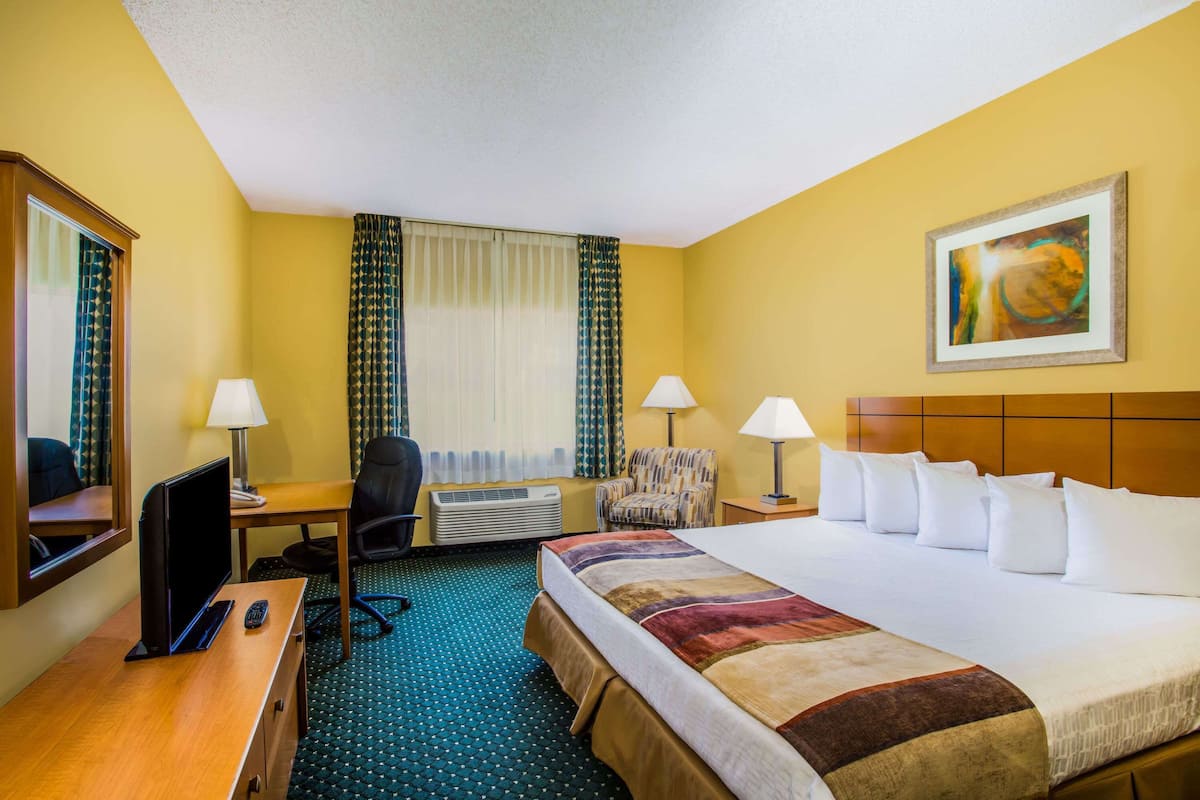 Ein Hotelzimmer mit Bett, Schreibtisch, Stuhl und Fernseher.