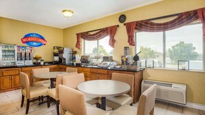 A breakfast corner with a round table and chairs, a coffee machine, and a refrigerator. - Baymont by Wyndham Helena (Helena)