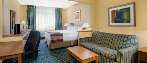 A hotel room with a bed, a sofa, a desk, and a chair.