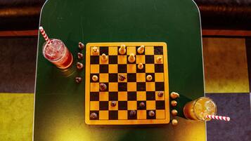 A chessboard on a green table with drinks and chess pieces.