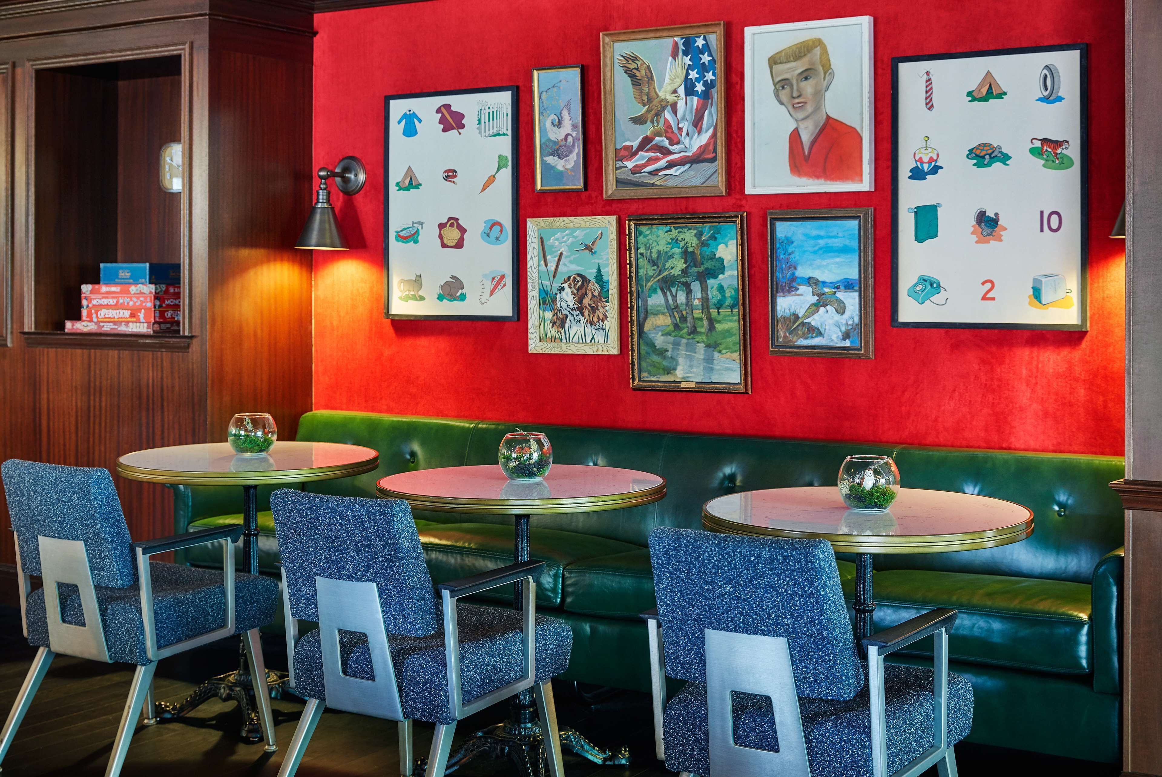 Un restaurante con asientos de tapicería verde, mesas redondas y sillas azules.