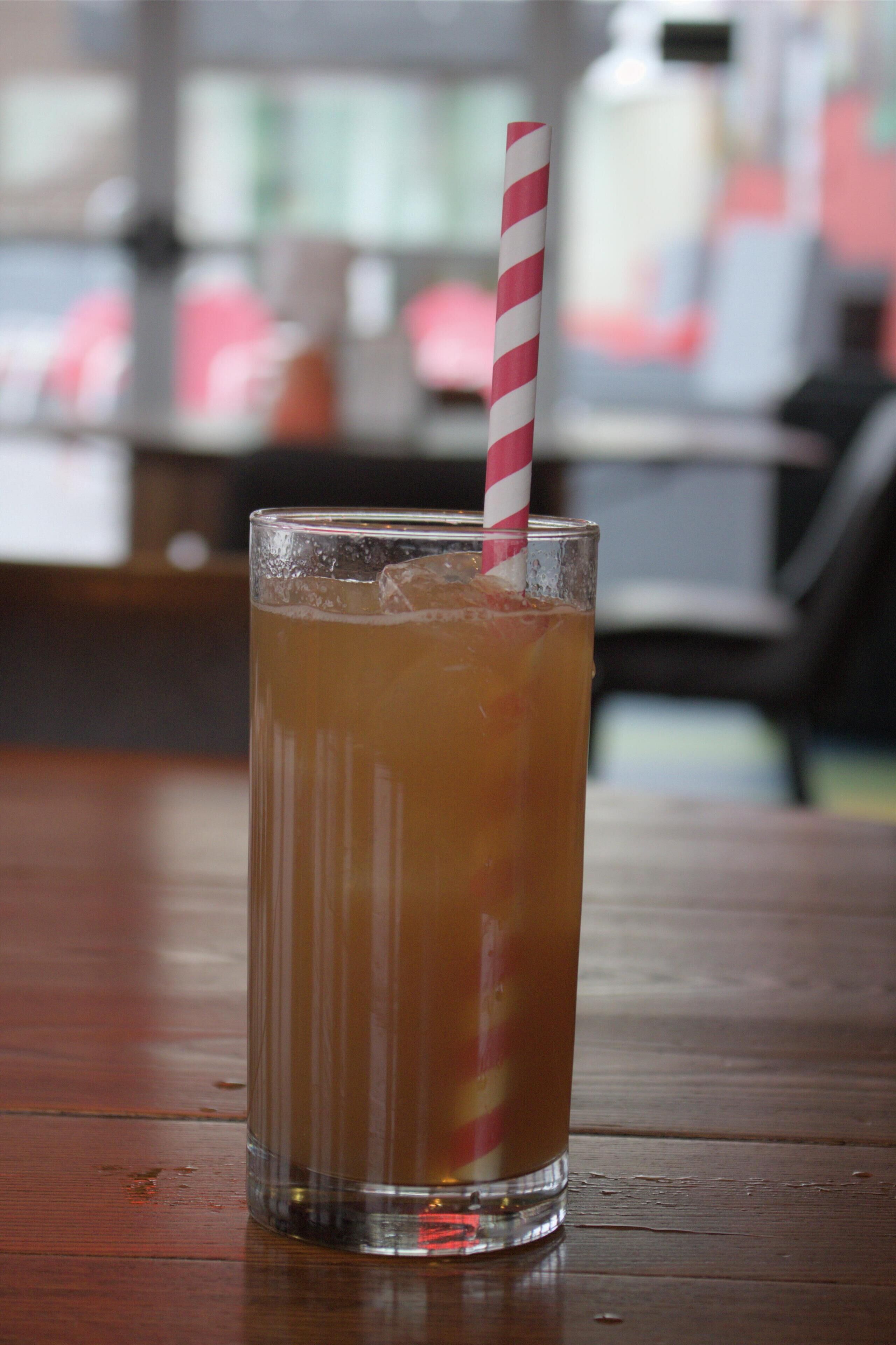 A tall glass with a striped straw on a wooden table.