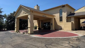 A building with a covered entrance, a red carpet, and a brick facade. - Days Inn by Wyndham Georgetown (Georgetown)