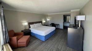 A hotel room with a bed, a desk, a chair, a refrigerator, and a lamp. - Days Inn by Wyndham Georgetown (Georgetown)