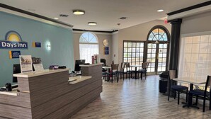 A Days Inn reception area with a wooden reception desk, a clock, and a large arched window. - Days Inn by Wyndham Georgetown (Georgetown)