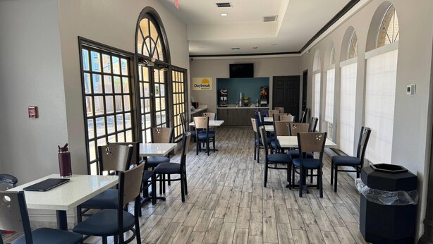 A restaurant with a central counter, multiple tables and chairs, and large windows. - Days Inn by Wyndham Georgetown (Georgetown)