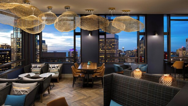 A modern lounge with wicker furniture, a wooden table, and hanging spherical light fixtures.