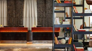 A reception area with a modern design, featuring a reception desk, a bookshelf filled with books, and a patterned wall.