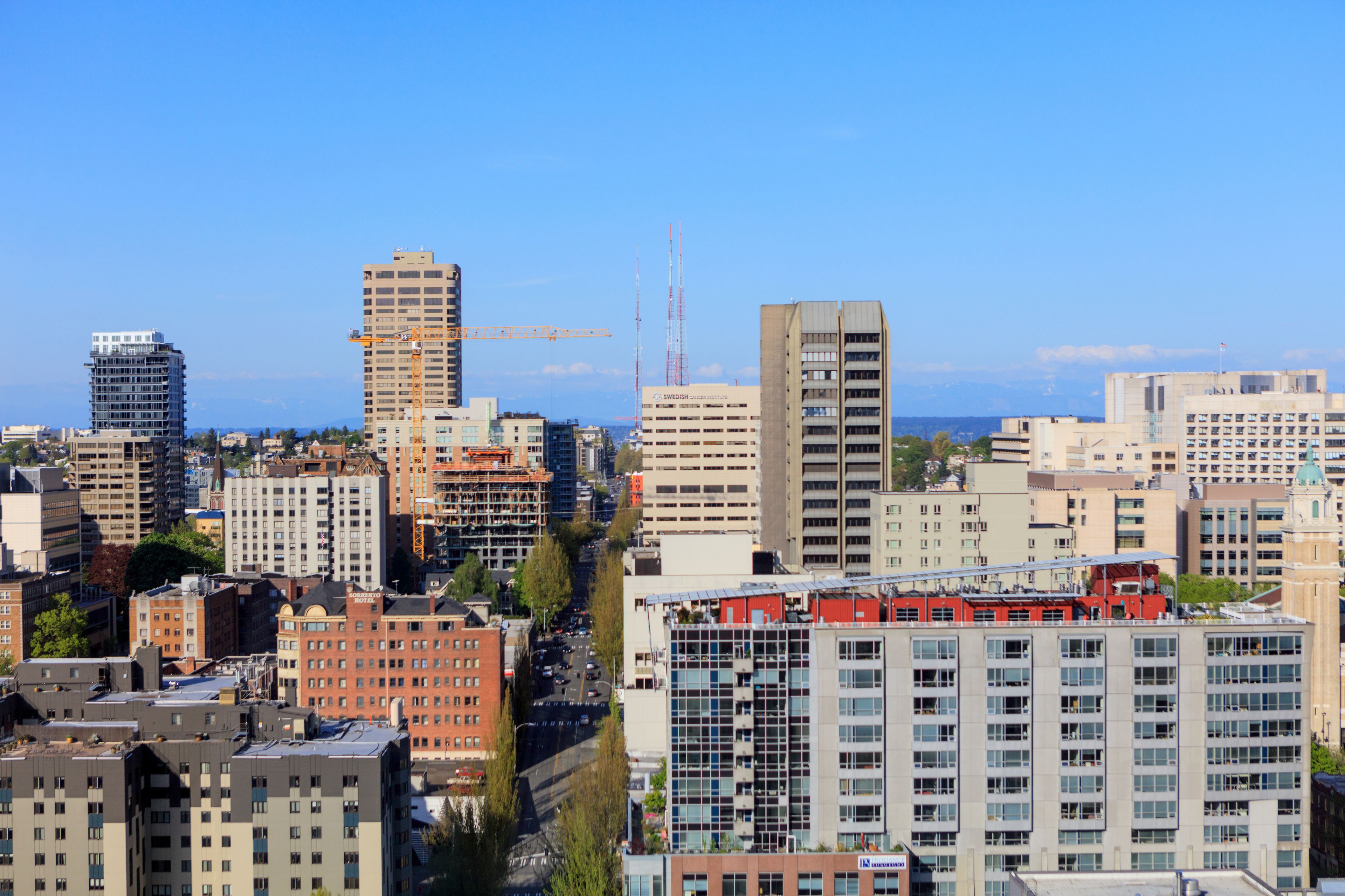 A cityscape with various buildings, including high-rises and mid-rise structures, under a clear sky.