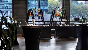 A bar area with multiple tables, a variety of bottles, and glasses.