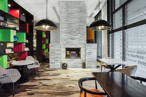 A modern lounge area with a stone fireplace, colorful shelving, and contemporary furniture.