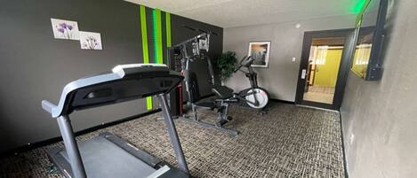 A gym with a treadmill, elliptical, and weight machines.