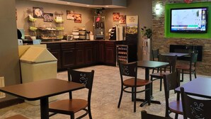 Un restaurante con una estación de café, zona de estar y un televisor montado en la pared.
