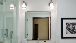 A modern bathroom with a glass shower enclosure, a white sink with a mirror above, and a framed picture on the wall. - The Crossroads Hotel, Newburgh (Newburgh)