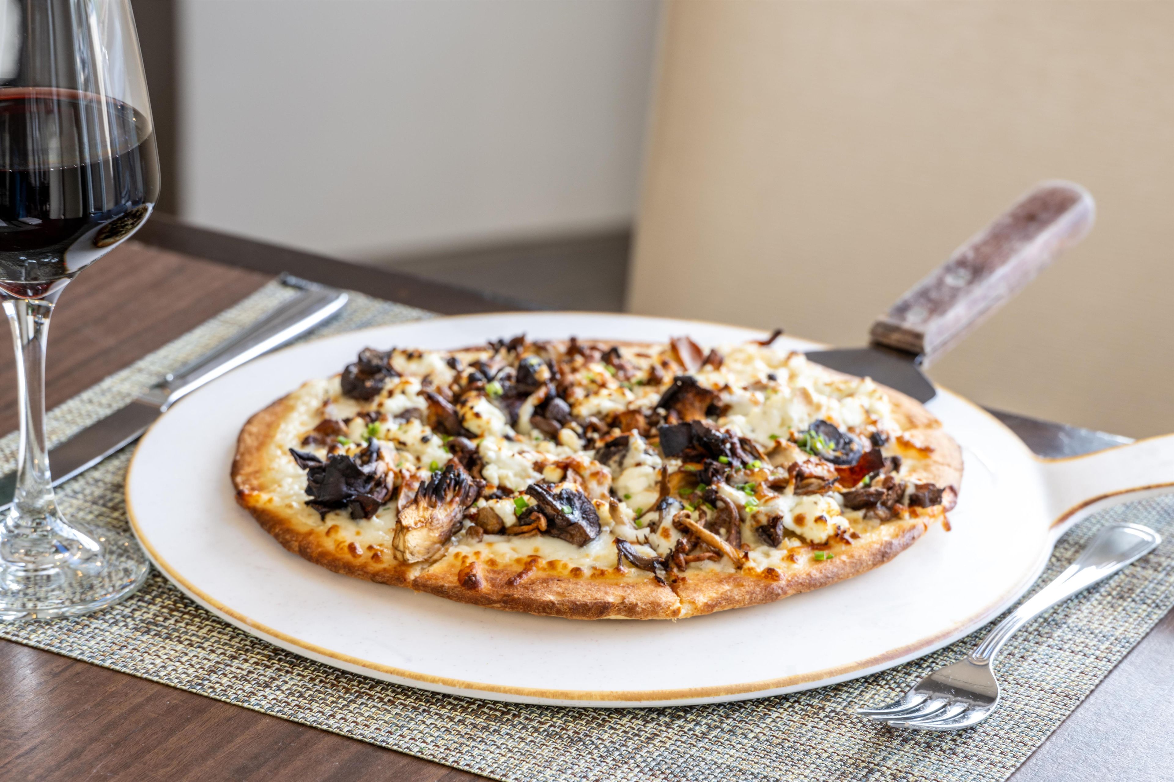 A pizza on a plate with a knife and fork beside it.
