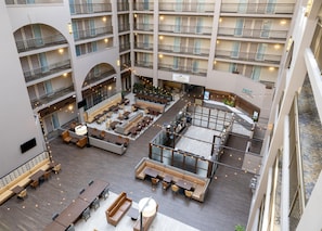 A multi-level hotel atrium with seating areas, a restaurant, and a sign for 'Cascades Delights.' - Embassy Suites by Hilton Seattle Bellevue (Bellevue)