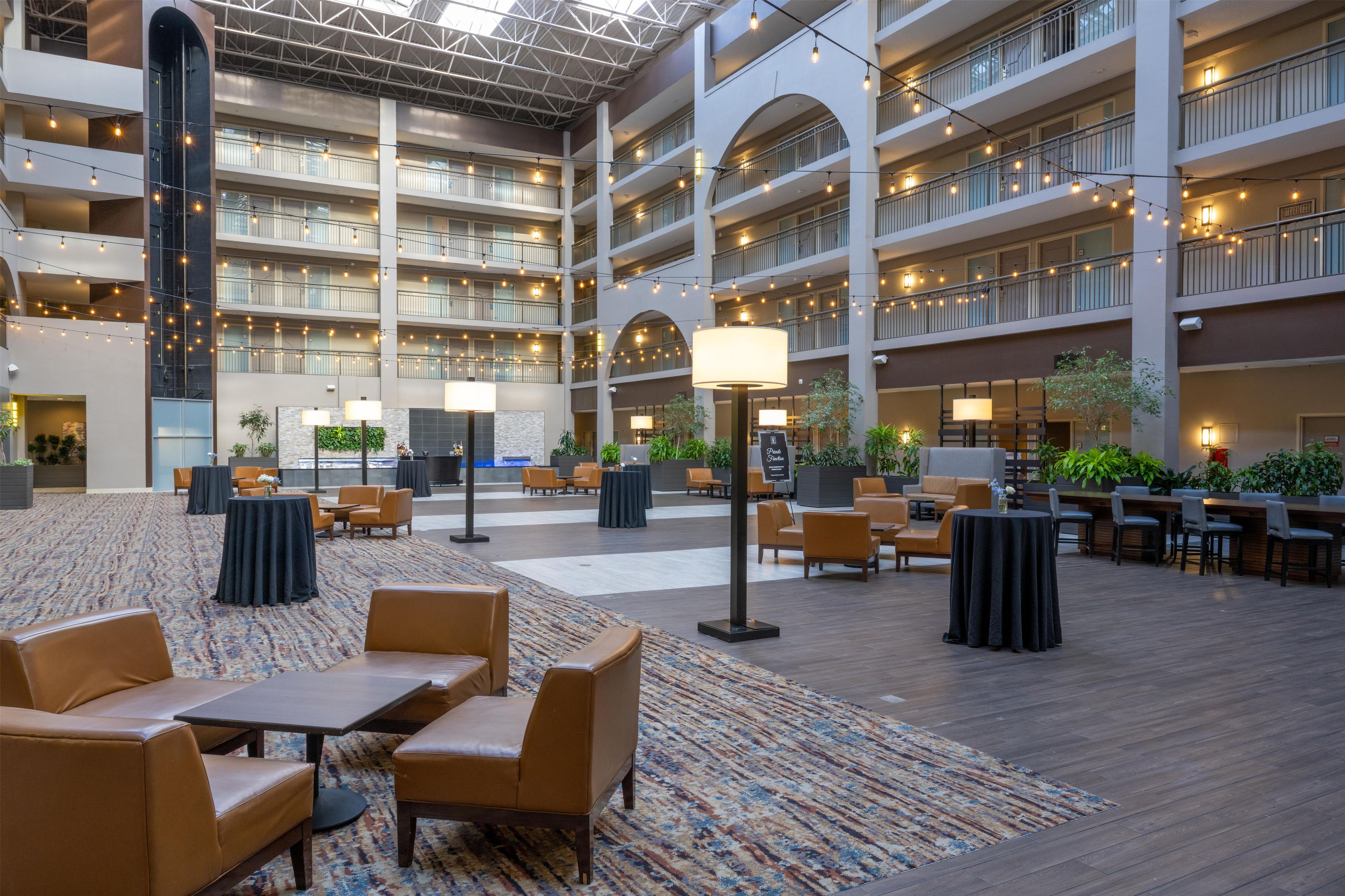 A multi-level hotel lobby with seating areas, a patterned carpet, and string lights.