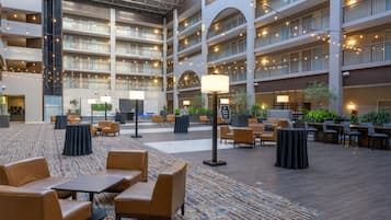 A multi-level hotel lobby with seating areas, a patterned carpet, and string lights.