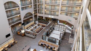Un vestíbulo de hotel de varios niveles con áreas de estar, un restaurante y un letrero que dice 'Cascades Delights'.