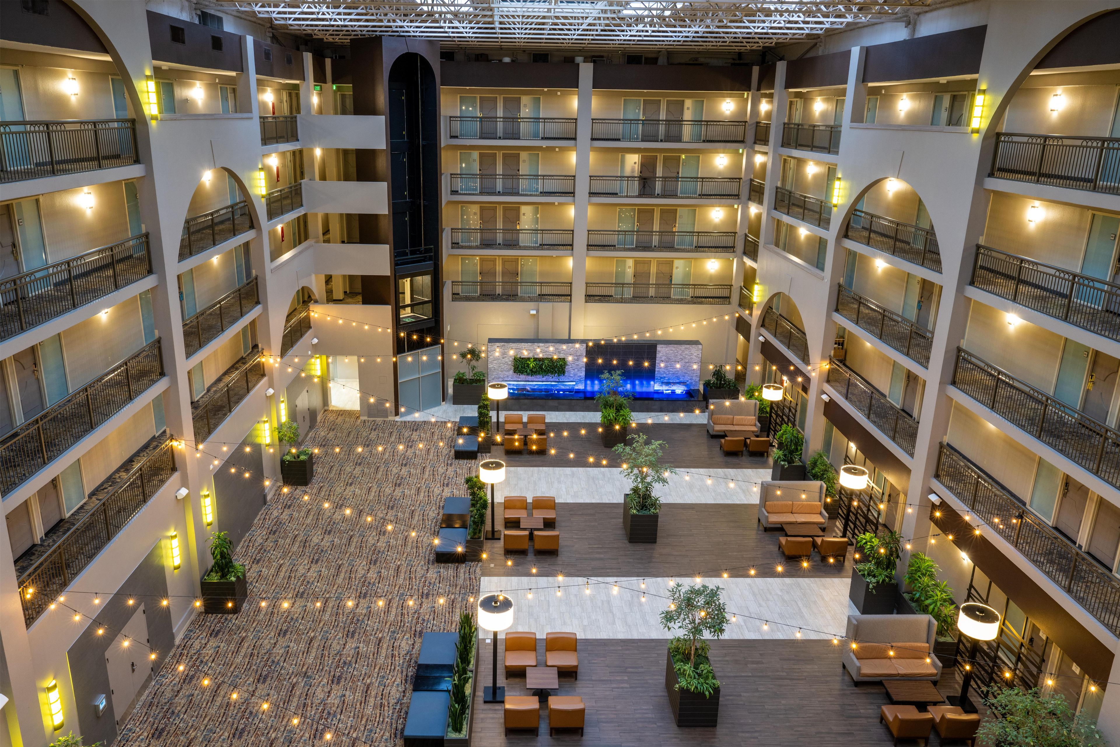 A multi-level hotel atrium with balconies, seating areas, and a central water feature.
