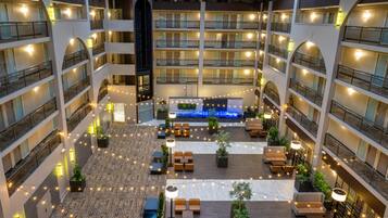 A multi-level hotel atrium with balconies, seating areas, and a central water feature.