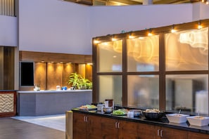 A buffet area with a counter, various food items, and a large window with frosted glass. - Embassy Suites by Hilton Seattle Bellevue (Bellevue)