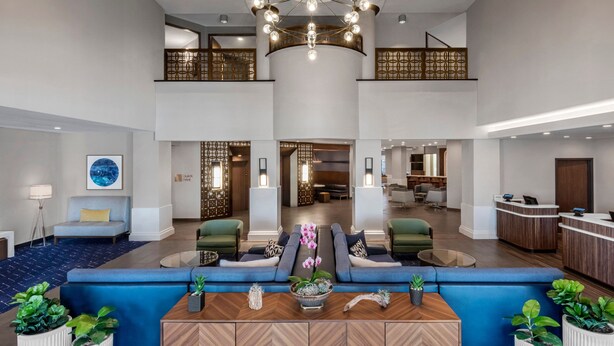 A spacious lobby with a central seating area, a reception desk, and a staircase leading to an upper level. - Courtyard by Marriott San Diego Miramar (San Diego)
