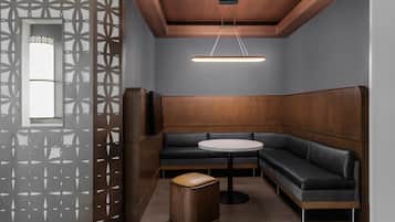 A modern interior with a wooden panel wall, a round table, a dark sofa, and a patterned partition.