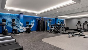 A modern gym with treadmills, weight machines, and a wall with a blue sky design. - Courtyard by Marriott San Diego Miramar (San Diego)