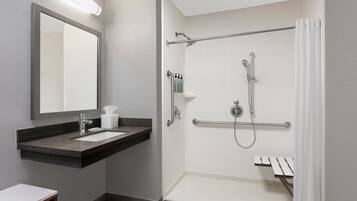 A modern bathroom with a vanity, mirror, shower, and towel rack.