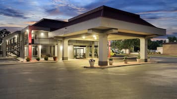 A hotel with a covered entrance, multiple floors, and a parking area.