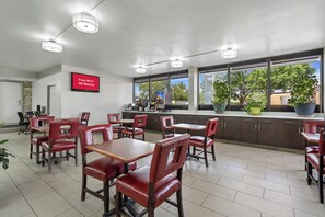 A restaurant with red leather chairs and tables, a kitchen area, and a sign indicating free Wi-Fi in all rooms. - Red Roof Inn Wilmington, NC (Wilmington)