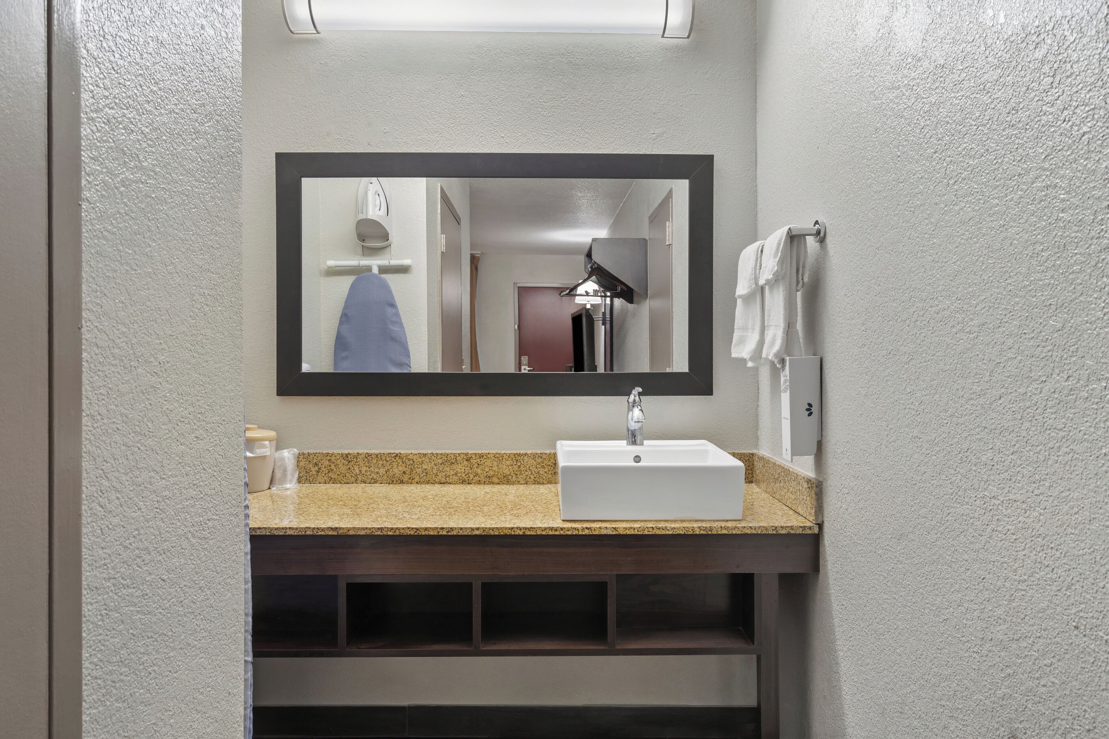 A bathroom with a rectangular mirror, a white sink, and a towel rack.