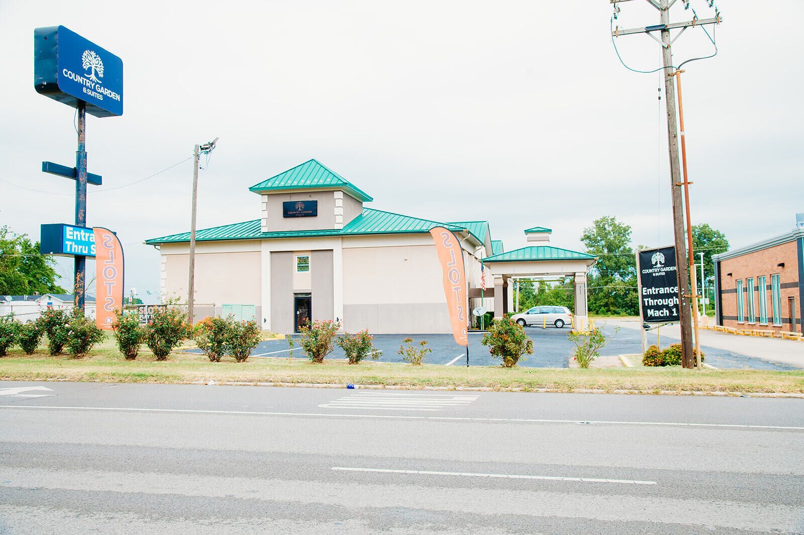 A Country Garden & Suites hotel with a green roof, a parking lot, and a sign indicating entrance through Mach 1.