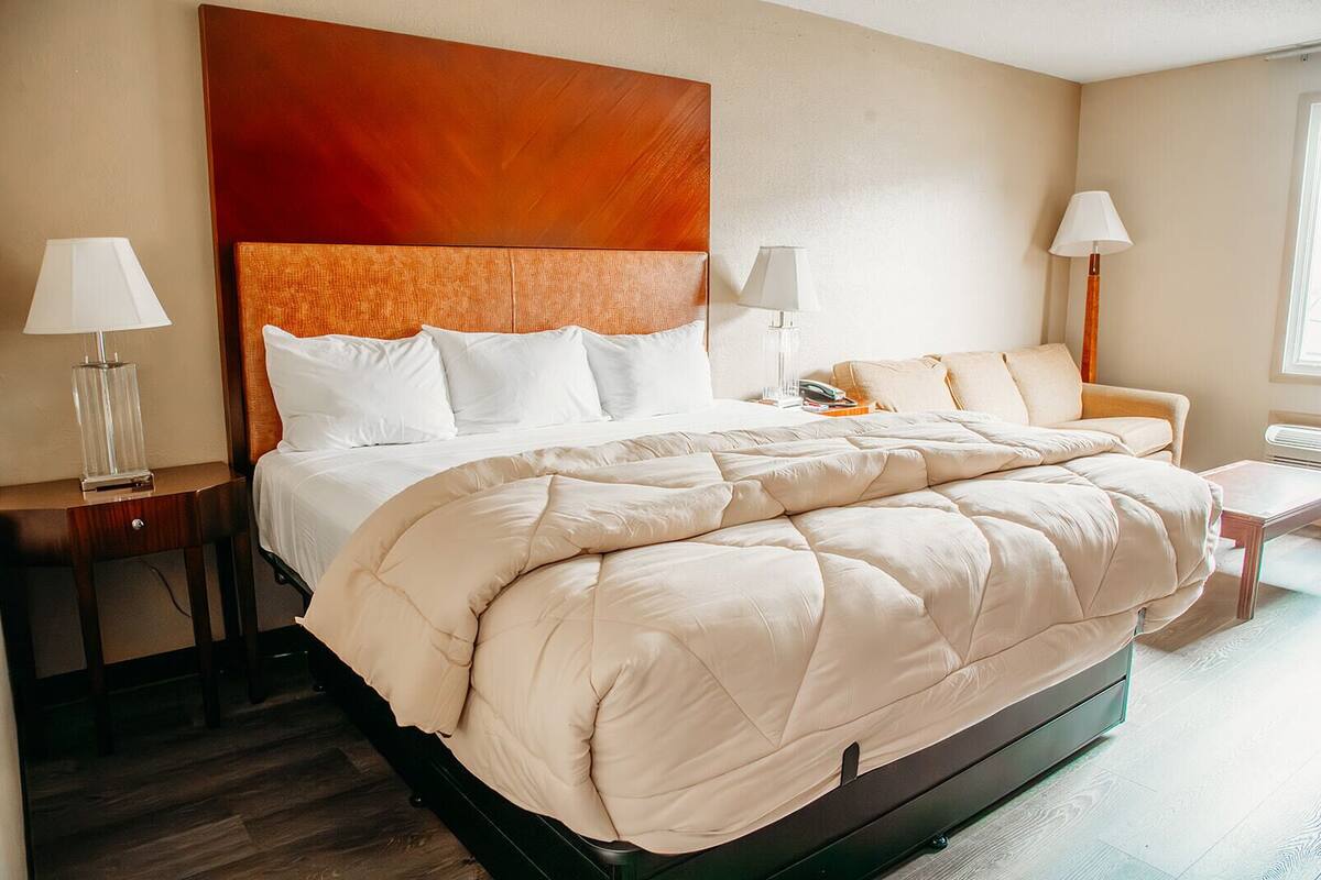 A hotel room with a large bed, two bedside tables, a chair, and a nightstand.