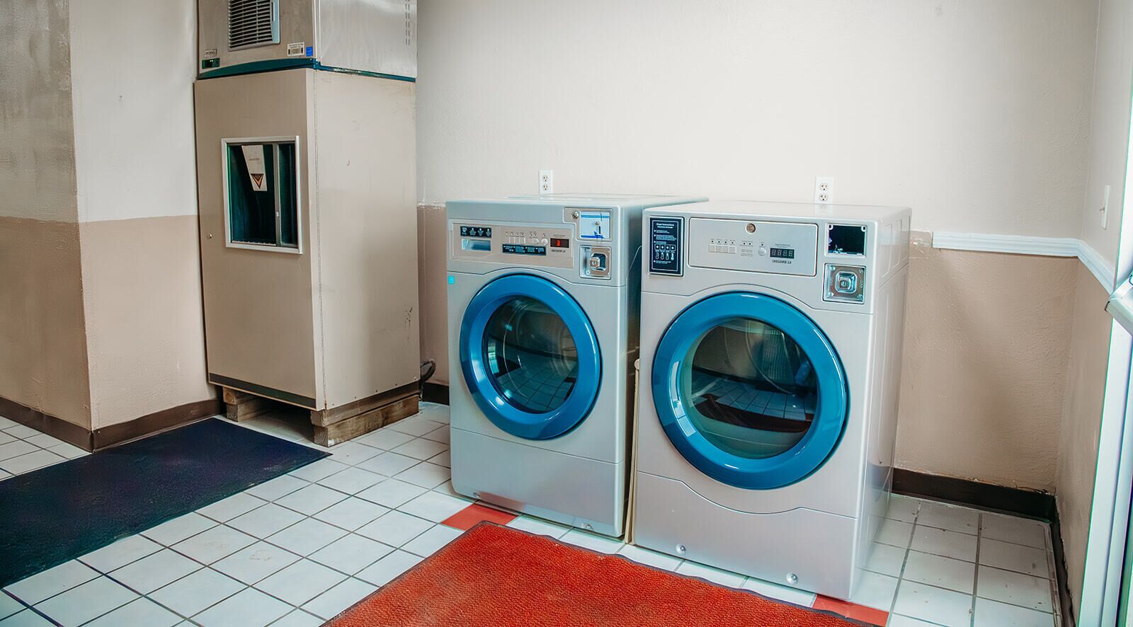 A laundry area with two front-loading washing machines and a dryer.